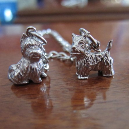 Two silver charms of terriers attached to a charm bracelet.